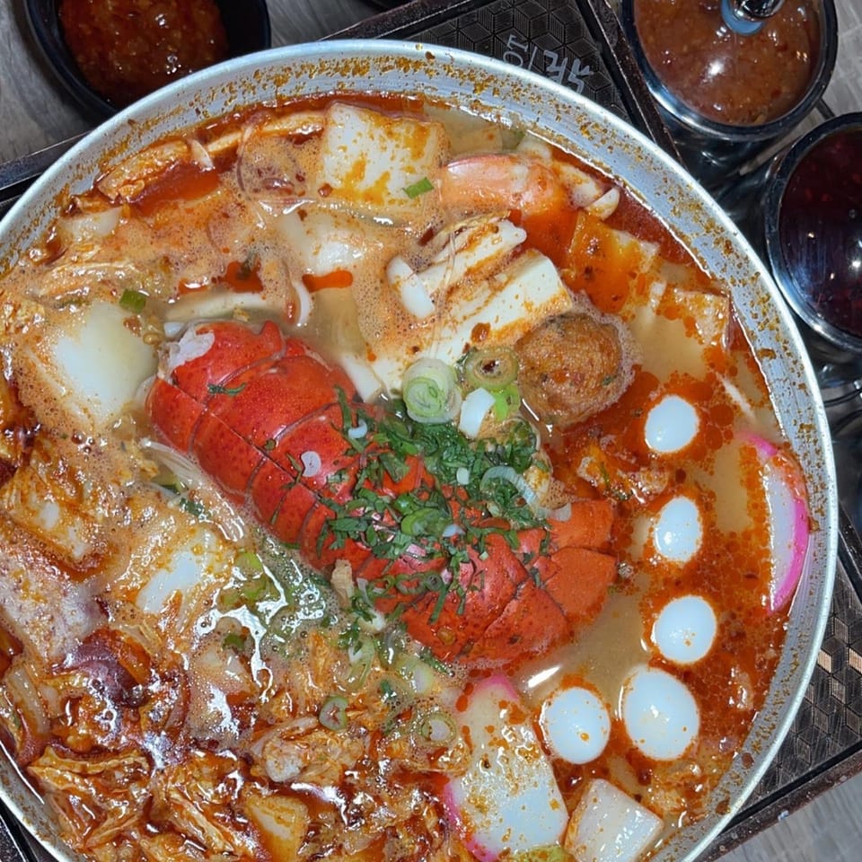 A close-up of a Taiwanese hot pot with lobster, tofu, fish cakes, and various other ingredients.