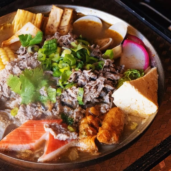 A close-up of a Taiwanese hot pot with various ingredients like meat, tofu, and vegetables.