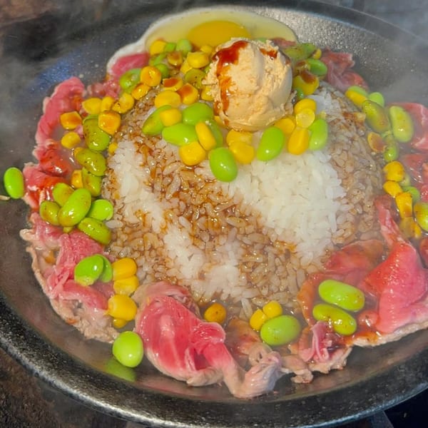 Sizzling Tasty Pot! beef hot pot with rice, corn, edamame, and an egg yolk.