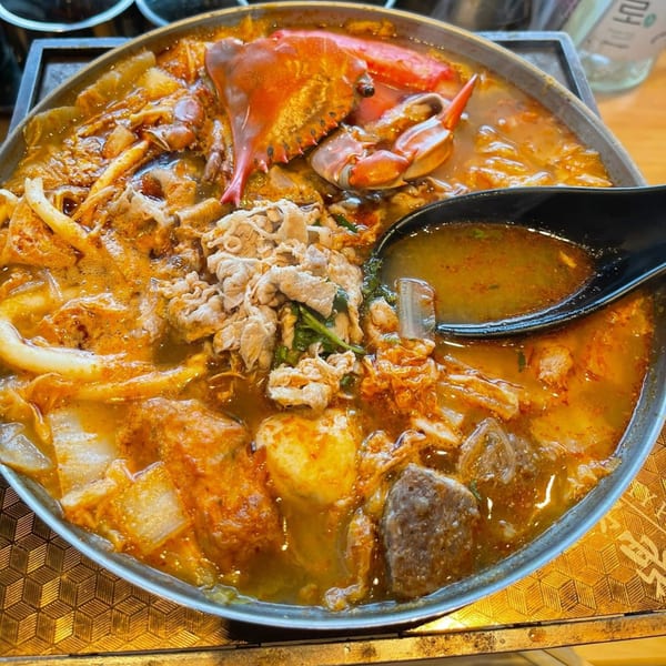 A Tasty Pot! Taiwanese hot pot with crab, sliced meat, and various ingredients in a savory broth.