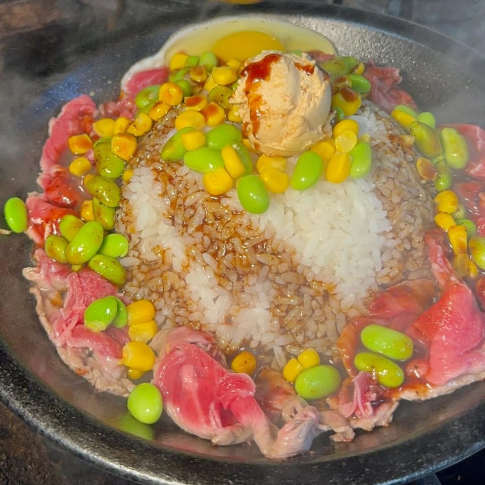 Tasty Pot! sizzling beef hot pot with rice, edamame, corn, and a raw egg yolk.