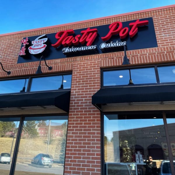 Exterior of Tasty Pot! Taiwanese Cuisine restaurant with a red brick facade and large windows.
