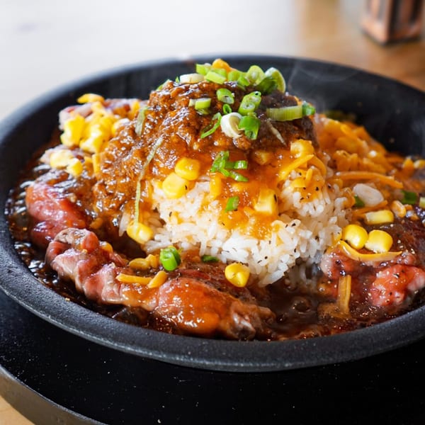 Sizzling Taiwanese beef hot plate with rice, corn, cheese, and green onions.